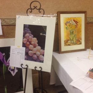 Art Silent Auction paintings, photos from local artists. Diane W., local artist and coordinator of art auction items.
